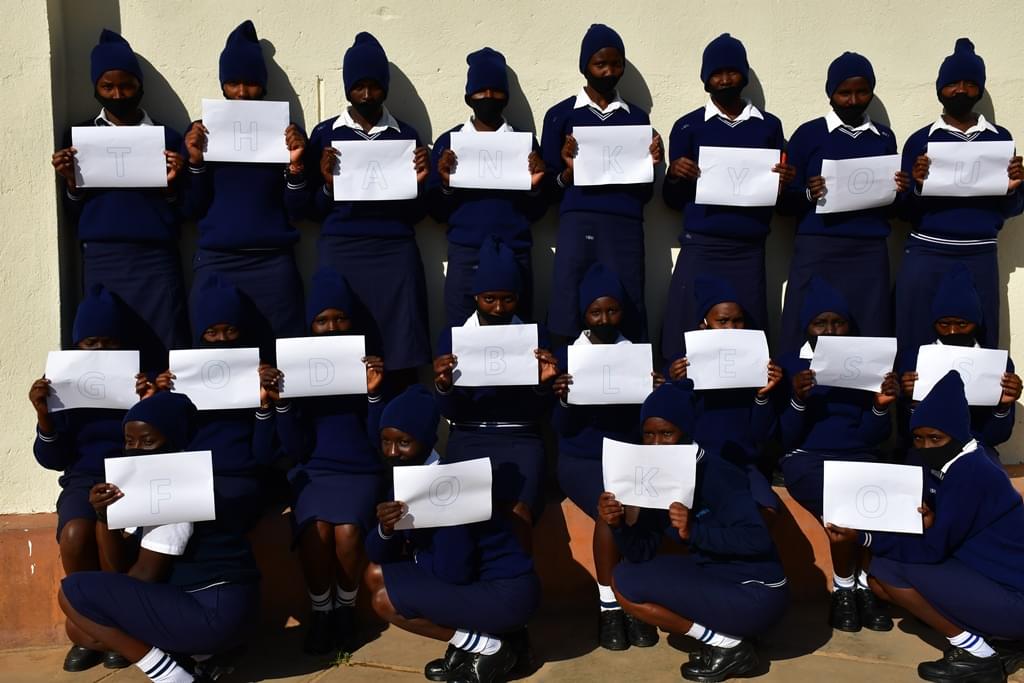 St. Clare students hold up a sign that reads 'Thank You, God Bless FOKO' 