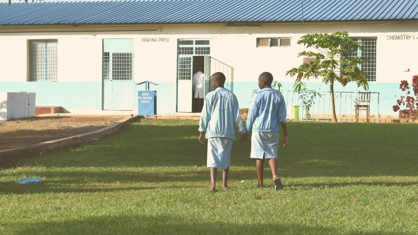 Two girls in school uniform holding hands